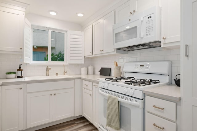 kitchen with white appliances, a sink, white cabinetry, light countertops, and recessed lighting