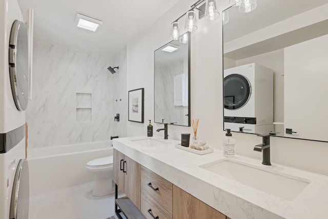 bathroom featuring stacked washer / dryer, toilet, bathing tub / shower combination, and double vanity