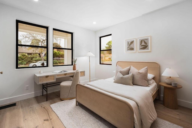 bedroom with multiple windows, wood finished floors, and visible vents