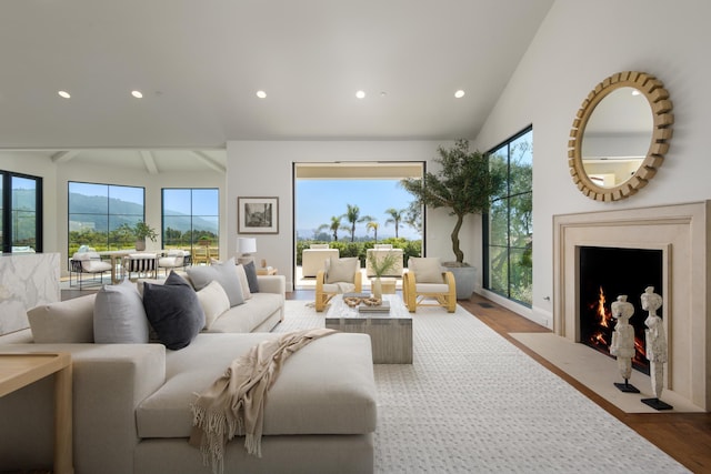 living room with a high end fireplace, wood finished floors, beamed ceiling, and recessed lighting