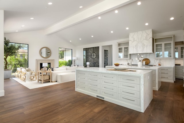 kitchen with white cabinets, glass insert cabinets, and vaulted ceiling with beams