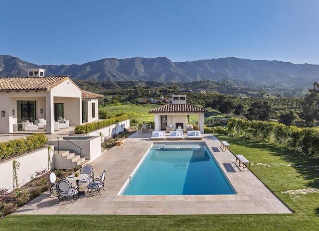pool with an outdoor hangout area, a mountain view, a patio area, and an outdoor structure