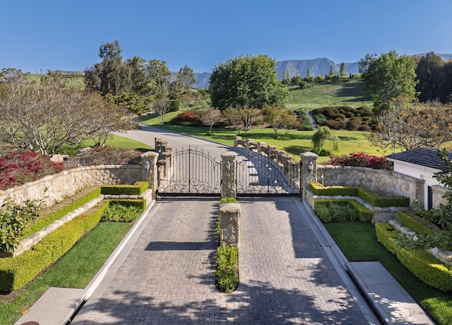 view of road with a gated entry, curbs, a mountain view, and a gate