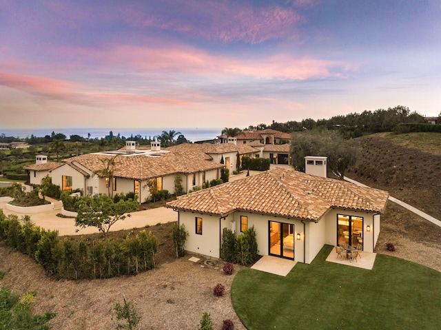 back of property at dusk featuring a patio, stucco siding, and a tiled roof
