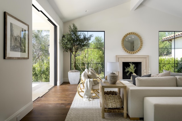 sitting room featuring a fireplace, wood finished floors, baseboards, and vaulted ceiling with beams