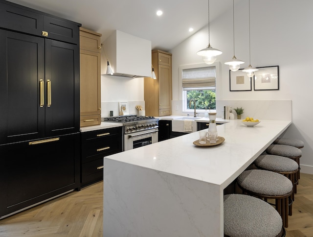 23 Calaveras Ave, Goleta, CA 93117 - kitchen with dark cabinetry, high end stainless steel range oven, a kitchen bar, a peninsula, and wall chimney exhaust hood