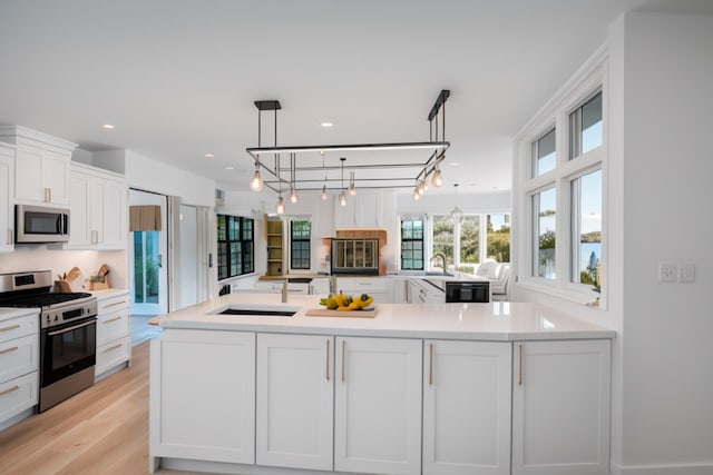 904 E Fir Ave, Lompoc, CA 93436 - kitchen featuring stainless steel appliances, white cabinets, light countertops, a sink, and light wood finished floors