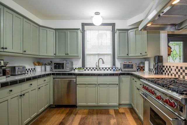 910 N Nopal St, Santa Barbara, CA 93103 - kitchen featuring stainless steel appliances, range hood, green cabinetry, tile countertops, and a sink