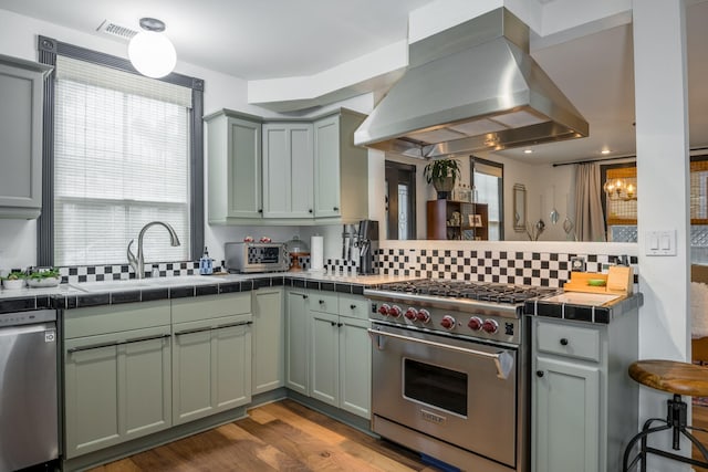 910 N Nopal St, Santa Barbara, CA 93103 - kitchen featuring island range hood, stainless steel appliances, a sink, a peninsula, and decorative backsplash