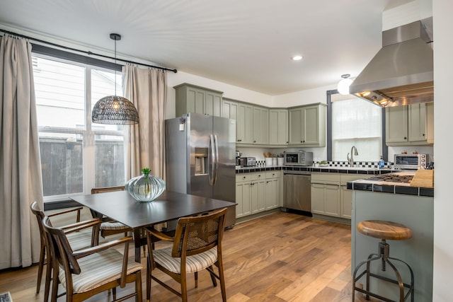 910 N Nopal St, Santa Barbara, CA 93103 - kitchen featuring stainless steel appliances, wall chimney exhaust hood, wood finished floors, a sink, and pendant lighting