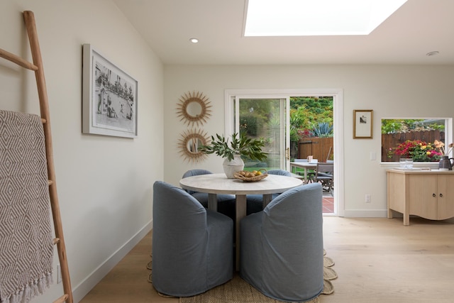 dining room with a skylight, light wood-style flooring, baseboards, and recessed lighting