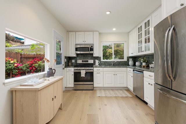 kitchen featuring stainless steel appliances, a sink, light wood-type flooring, tasteful backsplash, and recessed lighting