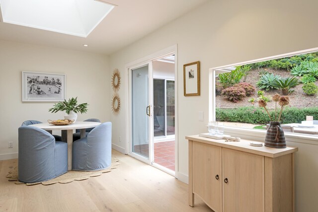 dining space with light wood finished floors, a skylight, baseboards, and recessed lighting