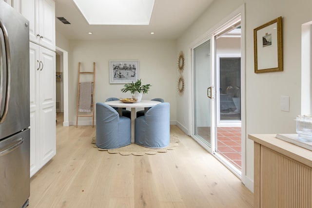 dining room featuring light wood-style flooring, a skylight, recessed lighting, and baseboards