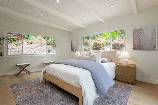 bedroom featuring multiple windows, light wood finished floors, baseboards, beamed ceiling, and recessed lighting