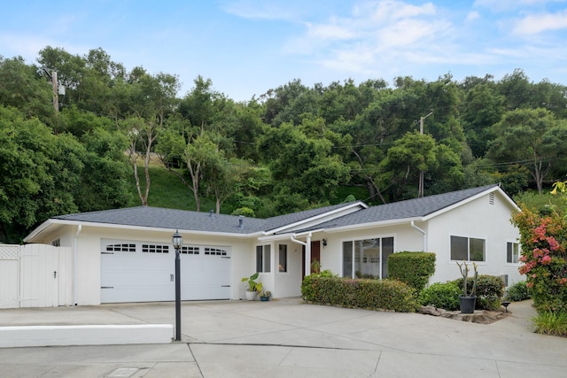 ranch-style house featuring a garage, concrete driveway, stucco siding, and a gate