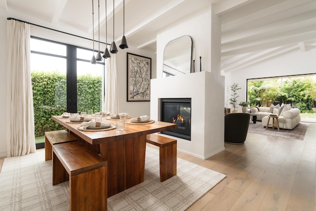 dining room with light wood finished floors, a multi sided fireplace, and lofted ceiling with beams