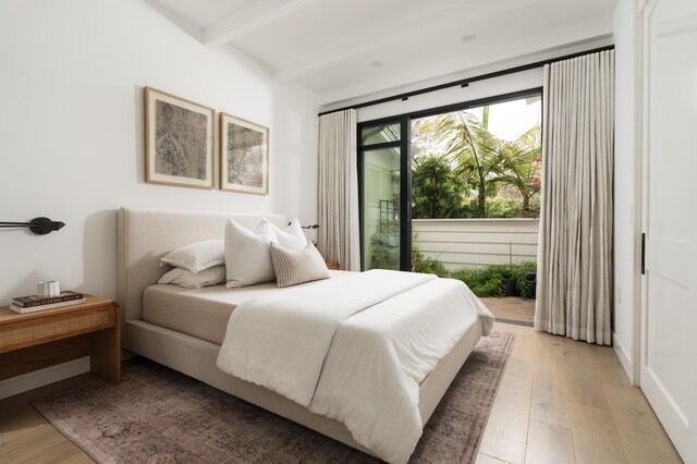 bedroom featuring beam ceiling, access to exterior, and light wood-type flooring