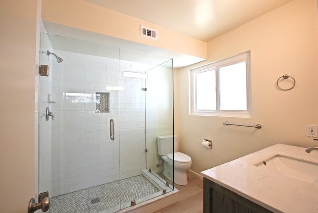 full bathroom with toilet, a stall shower, vanity, and wood finished floors