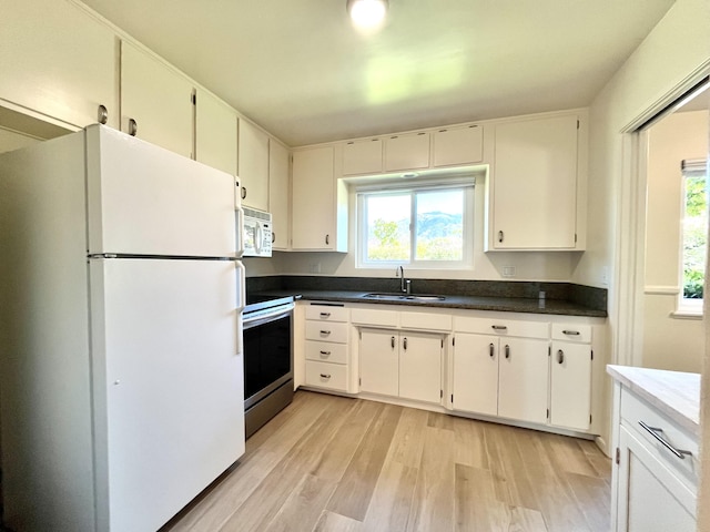 kitchen featuring white appliances, a sink, light wood-type flooring, and plenty of natural light