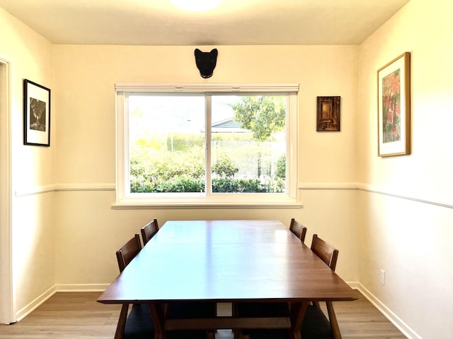 dining area with light wood-type flooring and baseboards