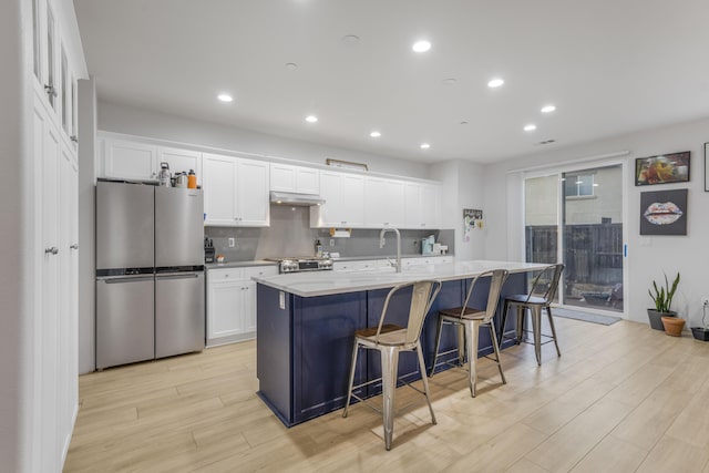 1010 Tranquillion Ct, Lompoc, CA 93436 - kitchen featuring freestanding refrigerator, light wood-style flooring, white cabinets, a kitchen island with sink, and recessed lighting