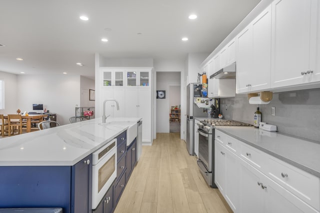 1010 Tranquillion Ct, Lompoc, CA 93436 - kitchen with under cabinet range hood, stainless steel gas range oven, a sink, white microwave, and white cabinetry