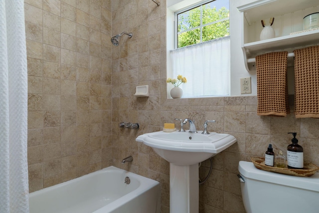 bathroom with shower / bath combo with shower curtain, toilet, and tile walls