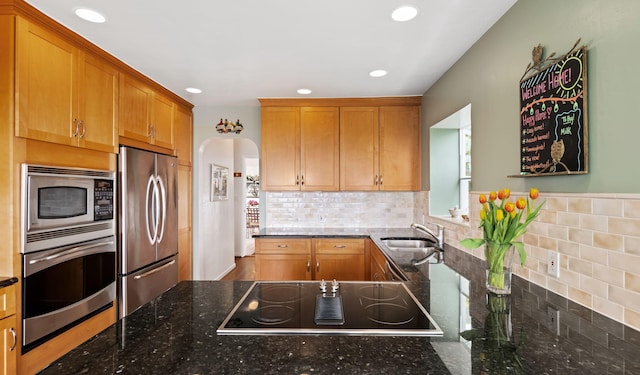 170 Loma Media Rd, Santa Barbara, CA 93103 - kitchen featuring appliances with stainless steel finishes, arched walkways, decorative backsplash, dark stone counters, and recessed lighting