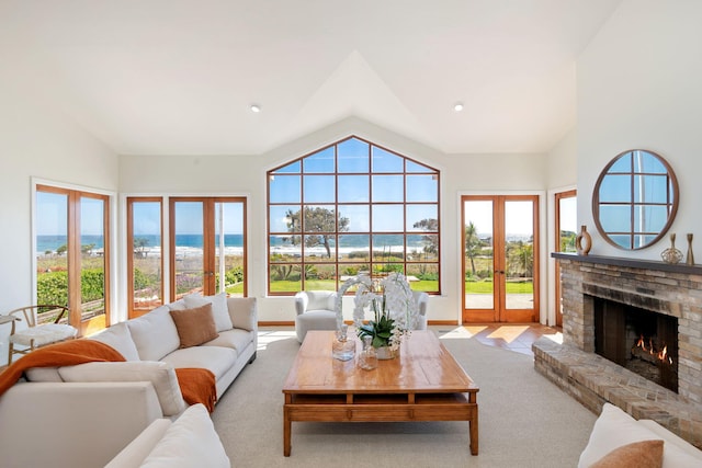 5529 Calle Arena, Carpinteria, CA 93013 - living room featuring french doors, vaulted ceiling, a brick fireplace, a water view, and carpet floors