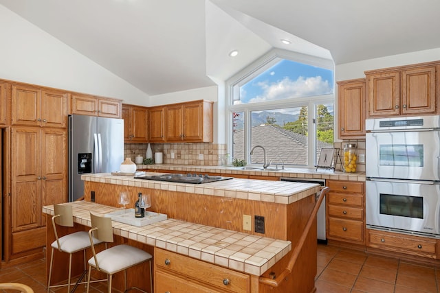 5529 Calle Arena, Carpinteria, CA 93013 - kitchen with vaulted ceiling, appliances with stainless steel finishes, tile counters, a sink, and tasteful backsplash