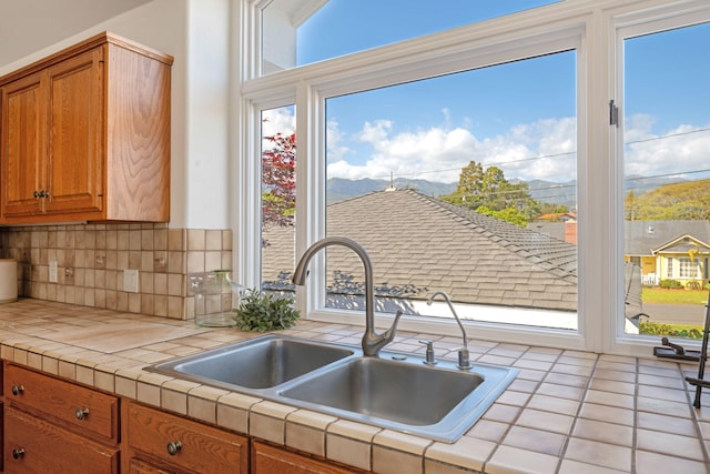 5529 Calle Arena, Carpinteria, CA 93013 - kitchen with tile countertops, a sink, tasteful backsplash, brown cabinetry, and healthy amount of natural light