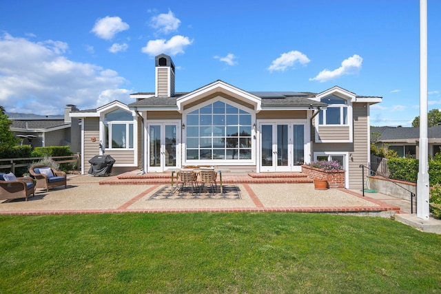 5529 Calle Arena, Carpinteria, CA 93013 - back of property with french doors, a lawn, a patio area, and solar panels