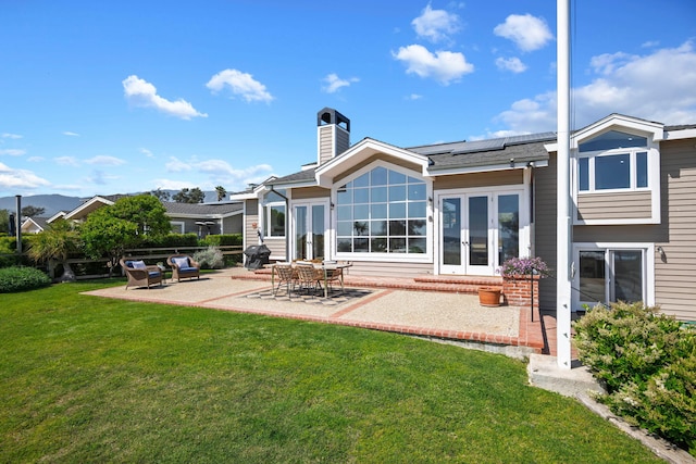5529 Calle Arena, Carpinteria, CA 93013 - back of house with french doors, a patio area, a yard, roof mounted solar panels, and a chimney