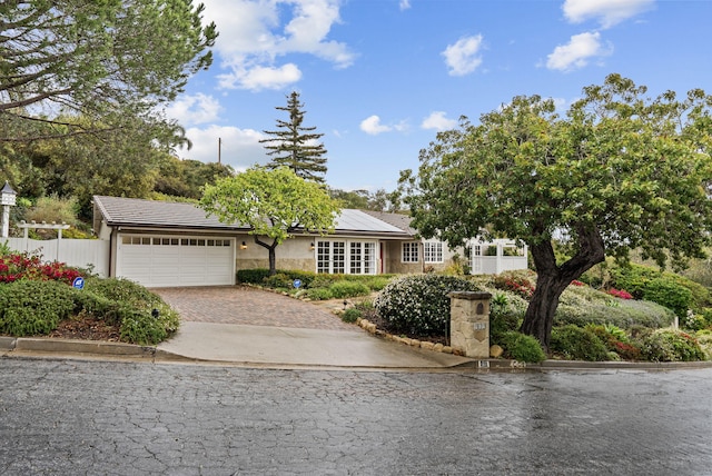 919 Aleeda Ln, Santa Barbara, CA 93108 - view of front of home featuring decorative driveway, a garage, roof mounted solar panels, and fence