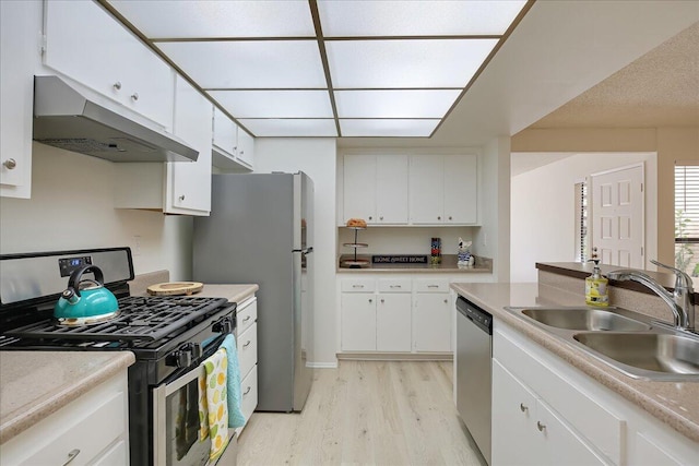 232 Rosewood St, Ventura, CA 93001 - kitchen with appliances with stainless steel finishes, under cabinet range hood, a sink, light wood finished floors, and white cabinetry