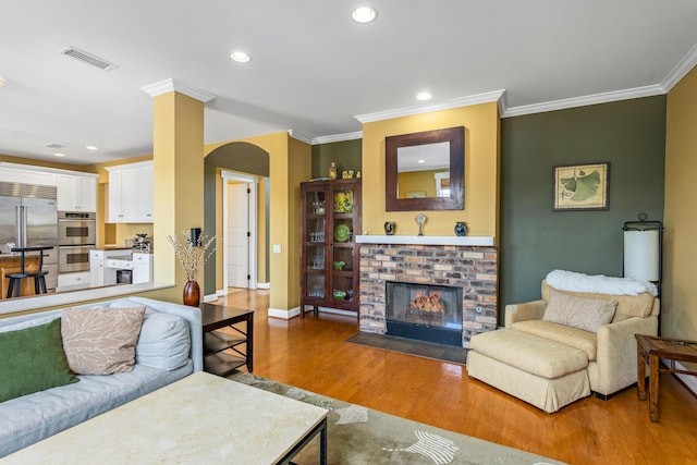 5049 Via Lara Ln, Santa Barbara, CA 93111 - living area featuring arched walkways, wood finished floors, ornamental molding, recessed lighting, and a brick fireplace