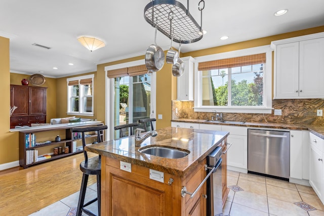 5049 Via Lara Ln, Santa Barbara, CA 93111 - kitchen with stainless steel dishwasher, a sink, light tile patterned floors, a center island with sink, and crown molding
