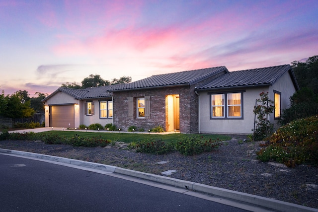 single story home featuring a tile roof, an attached garage, a lawn, concrete driveway, and stucco siding
