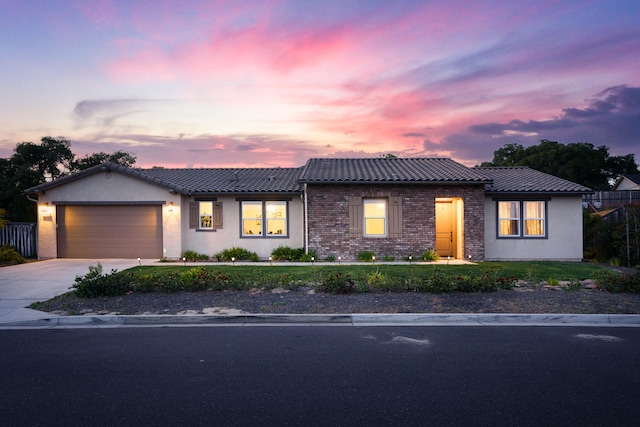 view of front of home featuring a tile roof, an attached garage, driveway, and stucco siding