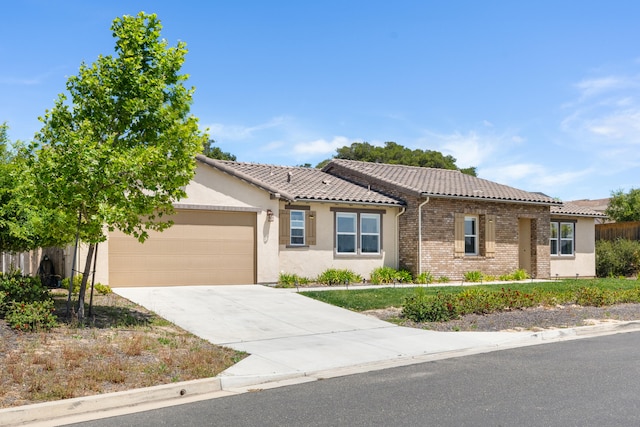 view of front of house with a garage, driveway, a tile roof, and stucco siding