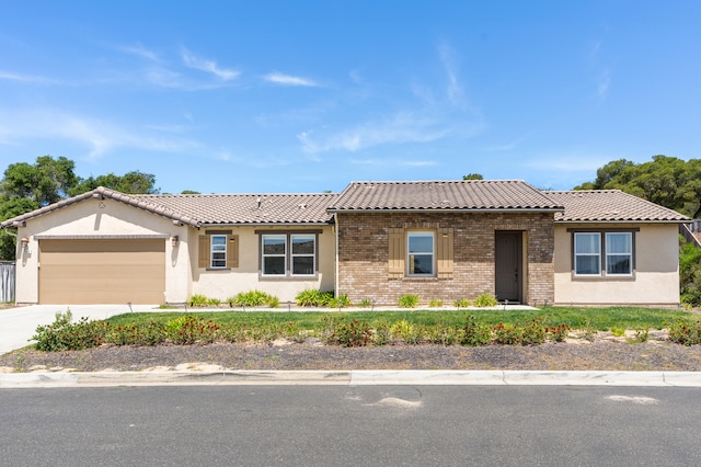 view of front facade featuring a tiled roof, a garage, brick siding, concrete driveway, and stucco siding