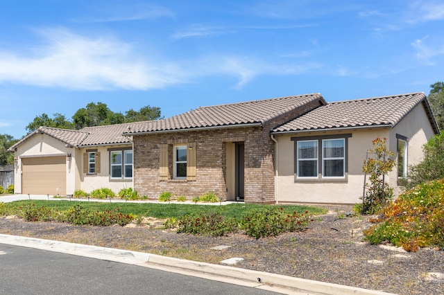 view of front facade with an attached garage, a tiled roof, and stucco siding