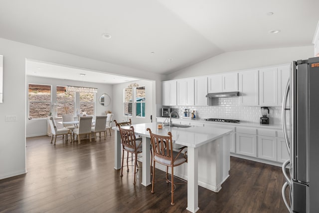kitchen featuring freestanding refrigerator, a sink, gas stovetop, under cabinet range hood, and lofted ceiling