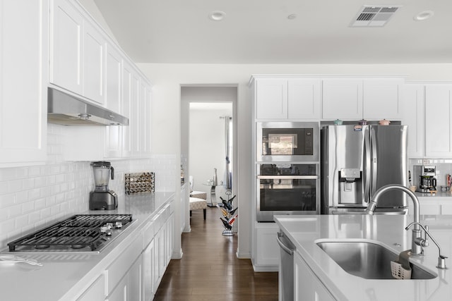kitchen featuring stainless steel appliances, under cabinet range hood, a sink, white cabinetry, and recessed lighting
