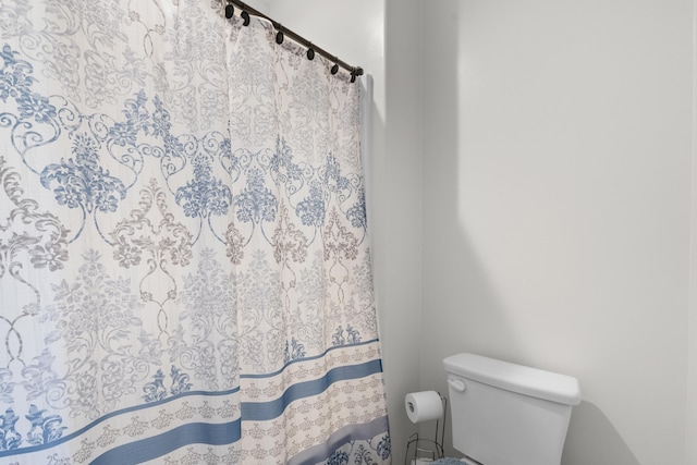 bathroom featuring toilet and curtained shower