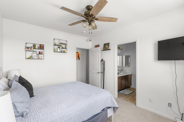 bedroom featuring light colored carpet, a sink, baseboards, connected bathroom, and a ceiling fan
