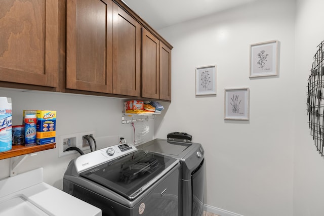 clothes washing area with washer and dryer and cabinet space