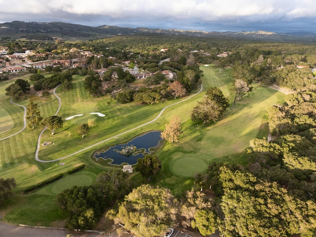 aerial view of property's location featuring a water and mountain view, a golf course, and nearby suburban area