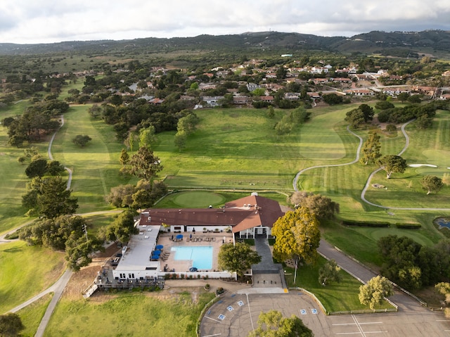 aerial overview of property's location featuring mountains, a pool area, and a golf course